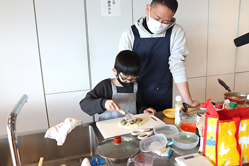 ピザをカットしている少年の写真 ピザをカットしている少年の写真